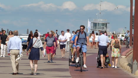 People-Walking-And-Biking-On-The-Promenade-Of-Knokke-Heist-Beach-On-A-Sunny-Summer-Day-During-The-Pandemic-Coronavirus-In-Flanders,-Belgium