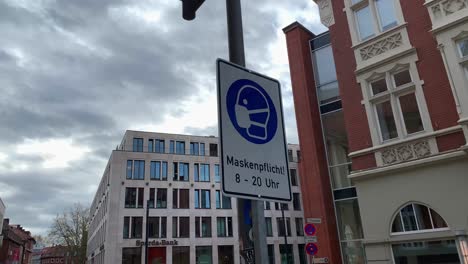 Close-up-shot-of-street-sign-with-mask-symbol-between-8-am-and-20-pm-in-Germany