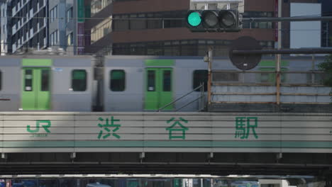 El-Rojo-Cambia-A-Verde-En-El-Semáforo-Con-Un-Tren-Japonés-Que-Pasa-Por-El-Cruce-De-Shibuya-En-Tokio,-Japón