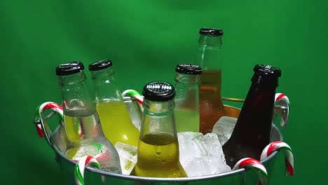 1-3-LOOP-Green-Screen-rotating-metalic-party-bucket-of-carbonated-Island-Soda-drinks-in-ice-with-hanging-candy-canes-and-water-droplets-on-glass-bottles-of-mango-ginger-pine-apple-lime-cola-cream