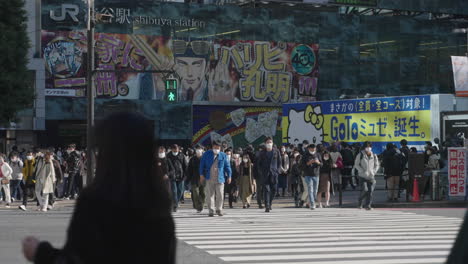 Fußgänger-überqueren-An-Der-Kreuzung-Shibuya-Scramble-Mit-Jr-Shibuya-Station-Im-Hintergrund-Während-Covid-19-In-Tokio,-Japan
