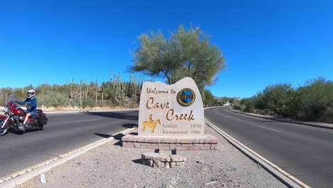 Traffic-in-and-out-of-Cave-Creek,-Arizona,-drive-past-the-Cave-Creek-welcome-sign