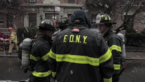 Group-of-Firefighters-evaluating-the-ConEd-electrical-fire-accident-in-Brooklyn-New-York-under-heavy-snow---Wide-Panning-shot