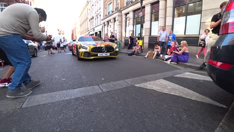 Crowd-admiring-Mercedes-AMG-GTR-performance-sports-car-Gumball-3000-luxury-driving-parade-London