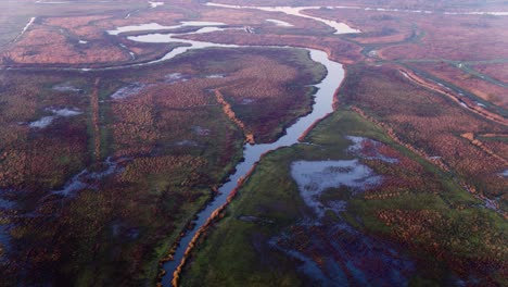 Scenic-river-delta-through-misty-reddish-reed-and-flooded-farmlands
