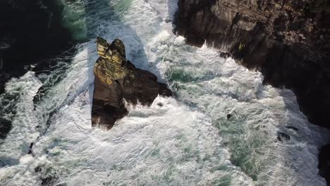 Rock-next-to-the-cliffs-of-Moher,-Ireland,-white-foam-of-the-big-waves-that-crash