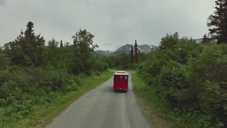 Anchorage-Trolley-Tours-In-Remote-Road-Passing-By-Dense-Forest-And-Snow-Mountains-Background-In-Alaska