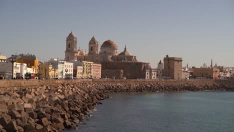 Beautiful-view-toward-Cadiz-cathedral-next-to-ocean-with-wave-breakers