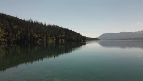 cinematic-Lake-Mcdonald-flying-low-on-top-of-the-lake,-national-forest-and-mountains