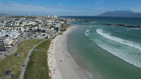 people-enjoy-summer-day-at-Big-Bay-Beach-in-Cape-Town,-South-Africa