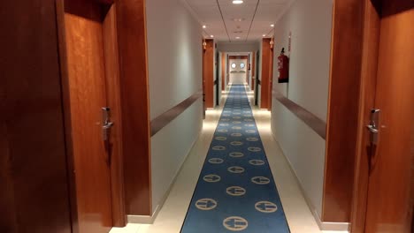 hotel-corridor-with-room-doors,-carpet-on-the-floor,-trash-can,-fireproof-systems-with-artificial-led-light