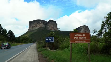 Tilting-down-landscape-shot-of-the-famous-Mount-of-Pai-Inácio-in-the-Chapada-Diamantina-national-park-in-northern-Brazil-on-a-warm-sunny-summer-day-from-the-highway-with-semi-trucks-passing-by