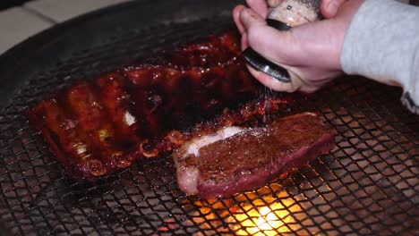 Caucasian-hands-grind-salt-on-tasty-steak-grilling-on-barbecue-braai