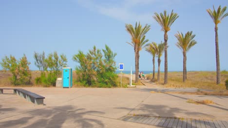Shot-of-palm-trees-park-with-the-view-of-sea-water-in-the-distance-at-Playa-El-Pinar-Beach-in-Grau-area,-Castellon,-Spain