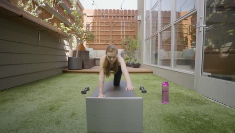 A-white-woman-doing-a-work-out-in-front-of-her-lap-top-while-training-virtually-with-her-trainer