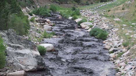Big-Thompson-river-blackened-by-ash-and-mud-following-a-mud-slide-in-a-burn-scar-area-near-Glen-Haven-Colorado-July-15,-2022