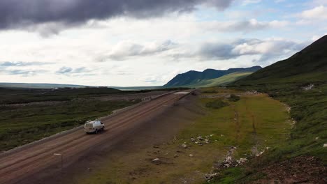 Luftverfolgung-Des-Lieferwagens,-Der-Auf-Einer-Unbefestigten-Straße-Durch-Die-Berge-Fährt-Und-Eine-Brücke-über-Stromschnellen-In-Alaska-überquert,-Sommersaison-Roadtrip