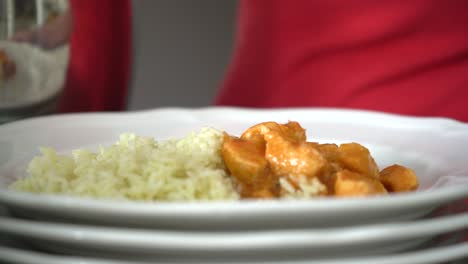 Loading-butter-chicken-onto-plate-with-rice,-Indian-food-cuisine,-close-up