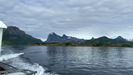 Static-shot-of-cruising-boat-with-a-stunning-landscape-of-mountains-and-clouds-in-the-background