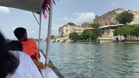 Indian-people-enjoying-boat-ride-through-big-lake-in-Udaipur-in-sunny-day,-India
