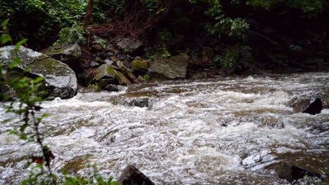 Wasser,-Das-An-Einem-Regnerischen-Tag-über-Felsen-In-Einem-überfluteten-Bach-Rauscht