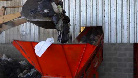 A-bulldozer's-bucket-unloading-the-waste-into-a-conveyor-belt's-hopper-inside-a-waste-processing-plant