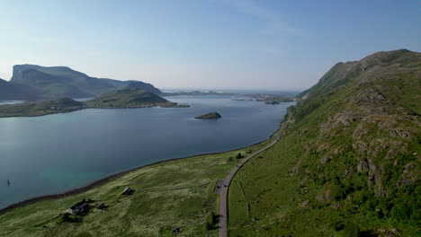 Aerial-High-angle-tucking-shot-along-Norwegian-costal-road-in-Lofoten-during-summer,-drone-shot