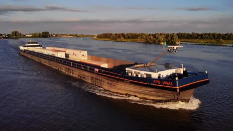 Aerial-Starboard-View-Of-Forward-Bow-Of-FPS-Waal-Cargo-Container-Vessel-Travelling-On-Oude-Maas-During-Golden-Hour
