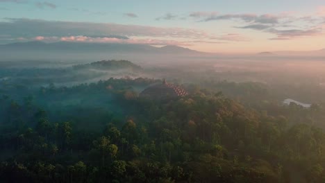 Schöner-Drohnenflug-Mit-Blick-über-Den-Borobudur-Tempel-Indonesien-Und-Die-Umliegenden-Berge-In-Einem-Orangefarbenen-Sonnenaufgang
