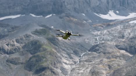Drone-dji-mini-3-pro-hovering-in-the-air-and-it-does-not-move-in-front-of-a-rocky-mountain-in-the-swiss-alps