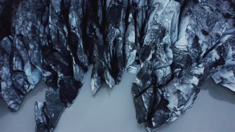 drone-shot-flying-backwards-with-camera-tilting-up-over-Solheimajokull-Glacier,-Iceland-4k