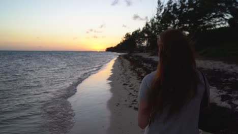 Red-headed-woman-taking-a-photo-on-her-iPhone-on-a-tropical-beach