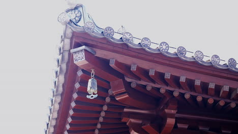 The-iron-bell-hanging-top-roof-in-a-Chinese-temple,-ringing-by-wind