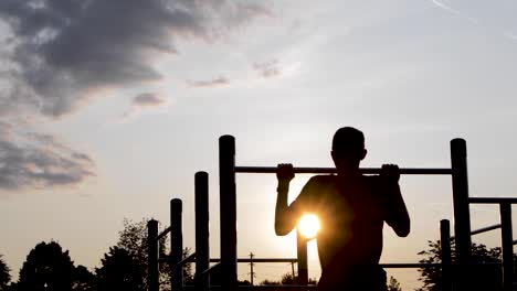 Young-Male-Exercising-On-Bar-at-Sunrise