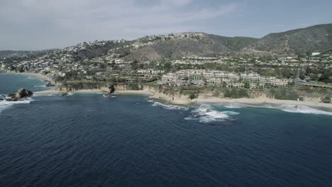 Cinematic-drone-shot-of-Laguna-Beach,-California-and-surrounding-mountains