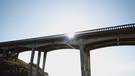 Blick-Auf-Eine-Alte-Kalifornische-Küstenbrücke-Mit-Der-Sonne,-Die-Durch-Die-Balken-Scheint