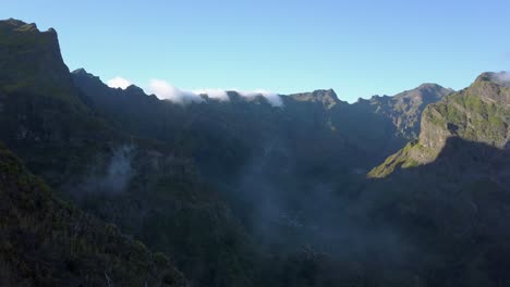 Madeira,-Portugal---Impresionante-Paisaje-De-La-Escarpada-Cordillera-Con-Niebla-Bajo-El-Cielo-Azul-En-Un-Día-Soleado---Toma-Aérea-De-Drones