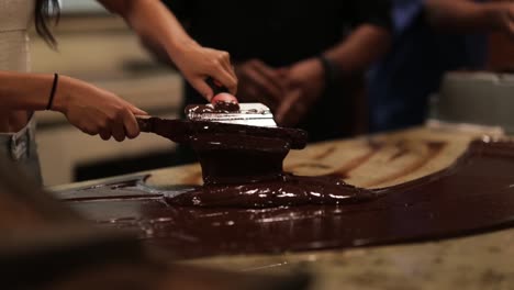 Girl-Tempering-Chocolate-Making-Process-With-Spatula-On-Granite-Counter