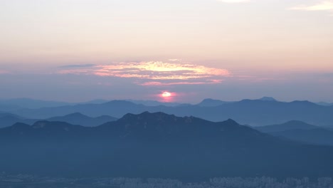 Orange-sunset-over-silhouetted-mountain-range-and-valley-in-South-Korea,-Asia