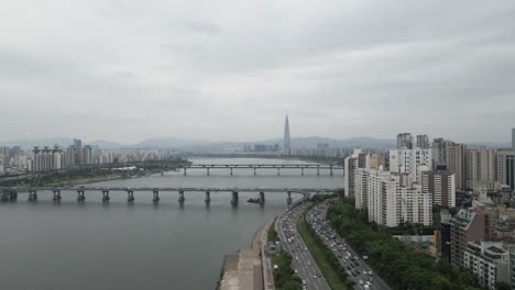 Aerial-shot-flying-over-Han-River-and-Seoul-city-with-Lotte-World-Tower,-South-Korea