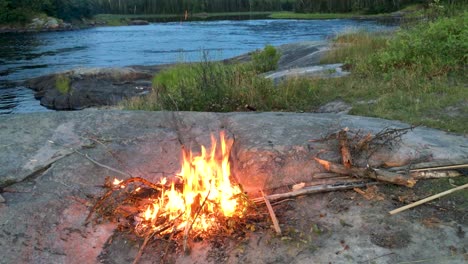 Canadian-boreal-shield-backcountry-campfire-on-rock-near-turbulent-Berens-river-Northern-Manitoba-Canada