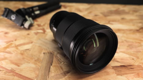 Close-up-Of-Camera-Lens-With-Tripod-On-Wooden-Table