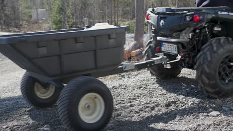 ATV-Quad-towing-a-plastic-trailer-on-a-wood-farm-in-the-forests-of-Sweden
