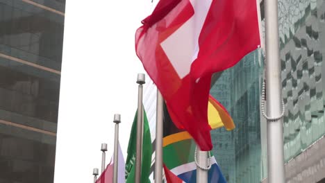 Nation-flags-of-Switzerland,-Spain,-South-Africa,-Saudi-Arabia,-Jordan,-New-Zealand,-Italy,-Hong-Kong,-and-China-are-seen-waving-in-the-wind-in-Hong-Kong
