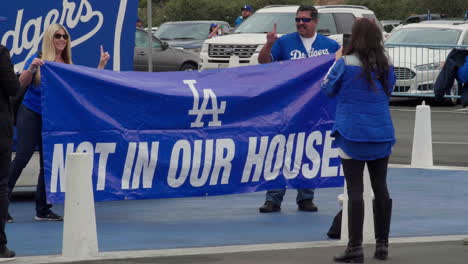 Los-Angeles-Dodgers-Sosteniendo-Un-Cartel-De-No-En-Nuestra-Casa-En-La-Calle-Entrando-Al-Estadio-De-Los-Dodger-Para-Ver-El-Partido-De-Béisbol