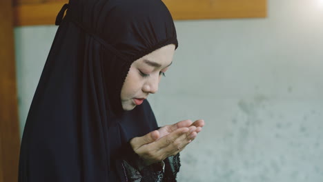 Portrait-of-an-Asian-Muslim-women-in-a-daily-prayer-at-home-reciting-Surah-al-Fatiha-passage-of-the-Qur'an-in-a-single-act-of-Sujud-called-a-Sajdah-or-prostration