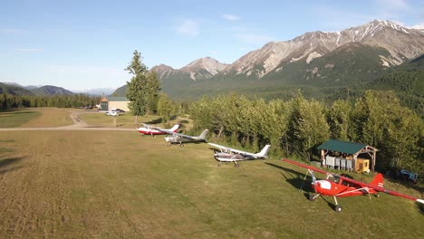 Aerial-footage-dolly-shot-along-airplanes-parked-along-a-grass-airstrip-in-the-Talkeetna-Range-of-Alaska