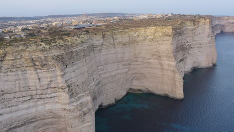 City-on-high-rugged-cliffs-of-Gozo-island-coastline,Malta,aerial-shot