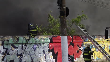 Pan-left-across-scene-from-fire-truck-to-black-smoke-wall,-firefighter