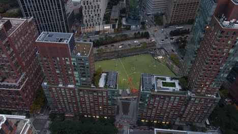 Aerial-view-overlooking-a-Ball-Field,-revealing-skyscrapers,-in-Tribeca,-New-York---tilt,-drone-shot
